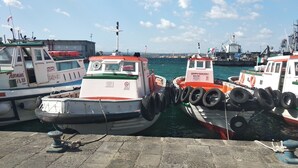 Un puerto con varias embarcaciones amarradas, que muestran nombres y logotipos en sus costados.