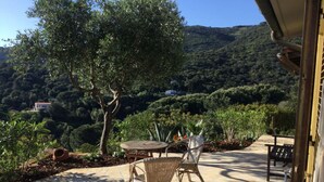 A patio with stone flooring, wicker furniture, and a view of a hillside. - Independent villa with splendid sea view terrace (Capoliveri)