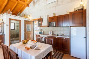 Una cocina con armarios de madera, un refrigerador blanco y una mesa de comedor con fruteros y velas.