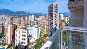 Un immeuble de grande hauteur doté de nombreux balcons et offrant une vue sur un paysage urbain avec des montagnes en arrière-plan.
