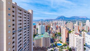 Un immeuble de grande hauteur, doté de nombreux étages, un paysage urbain avec différents bâtiments et des montagnes en arrière-plan.
