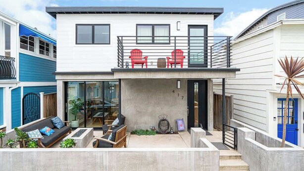 A two-story house with a balcony, outdoor seating area, and a garage. - Newport Beach Modern Home steps to the Beach (Newport Beach)