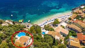 Vista aèria d'una zona costanera amb una platja, aigües blaves cristal·lines i un barri residencial.