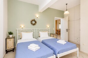 Une chambre avec deux lits, une petite table, une plante en pot et une armoire.