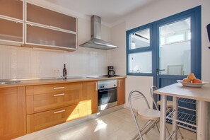 A modern kitchen with wooden cabinets, a stainless steel range hood, and a window with blue trim.