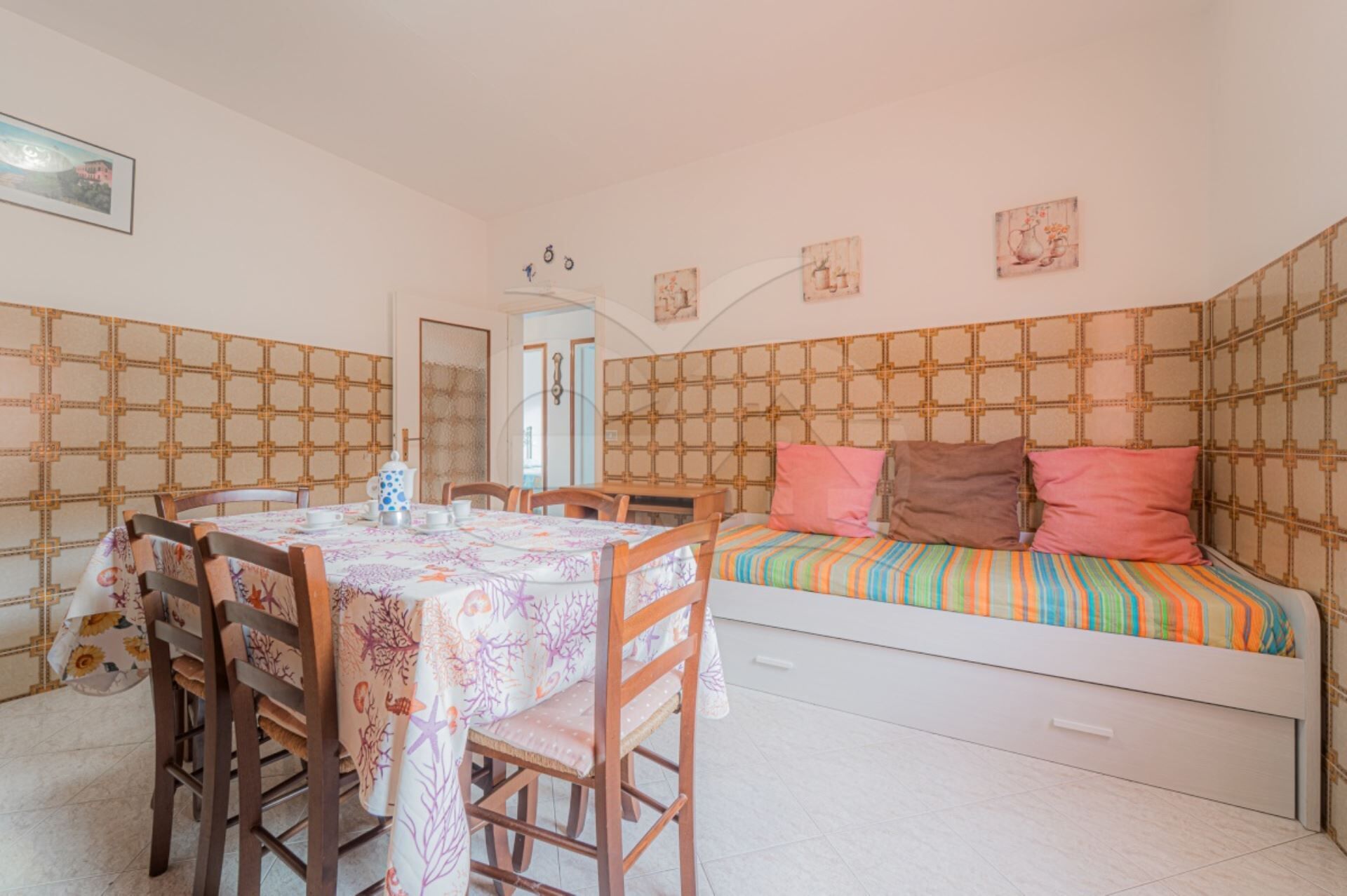 A cozy bedroom with a bed, a dining table with chairs, and a small kitchenette area.