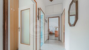 Un pasillo con puertas de madera, un panel de vidrio y un espejo en la pared.