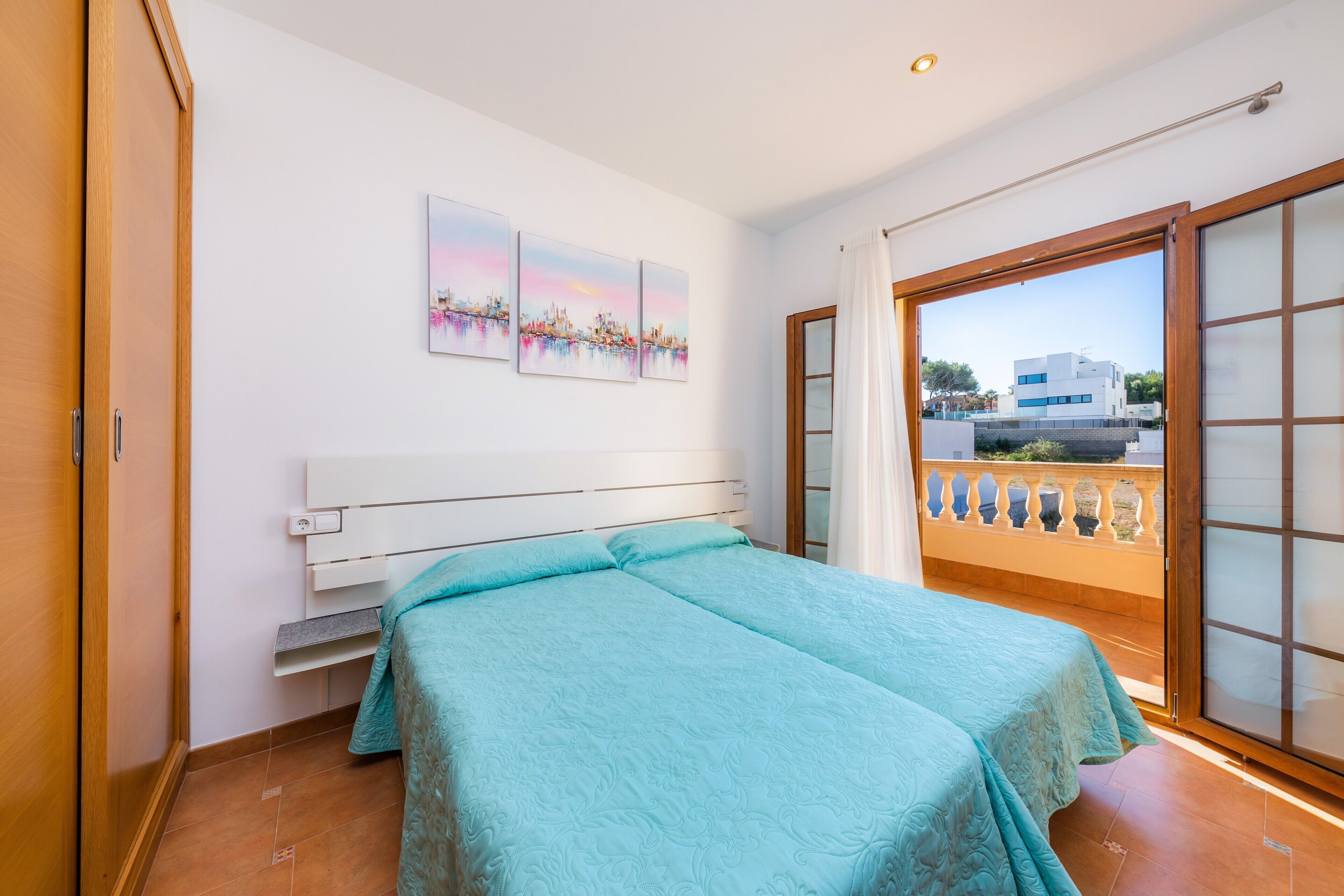A bedroom with a bed, a window, and a balcony.