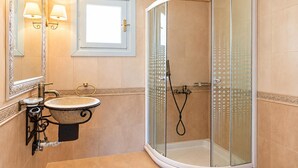 Une salle de bain dotée d’une douche à parois courbes en verre, d’un lavabo avec un receveur décoratif et d’un éclairage fixé au mur.