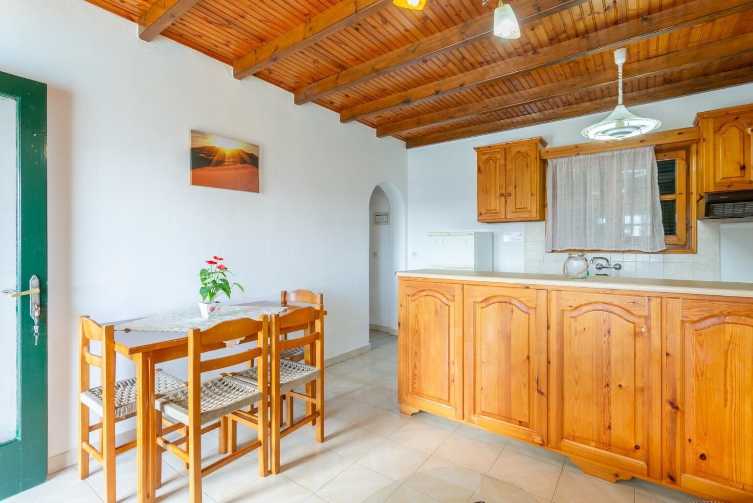 A kitchen with wooden cabinets, a dining table with chairs, and a ceiling with exposed beams.