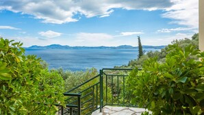 Un balcon offrant une vue sur une vaste étendue d’eau et sur des montagnes lointaines.
