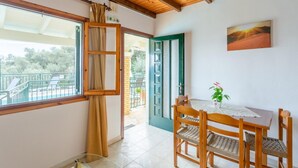 Une pièce avec un plafond en bois, une table à manger avec des chaises, une porte verte et une vue sur l’extérieur.