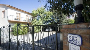 Une entrée fermée par un portail, avec une plaque indiquant le numéro de la maison, un mur en briques et un balcon.