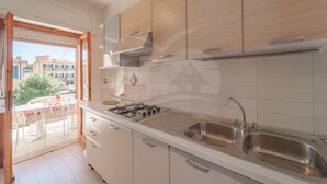 Une cuisine moderne avec des meubles blancs, un évier en acier inoxydable et une cuisinière à gaz.
