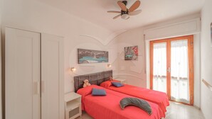 Une chambre avec deux lits, un ventilateur de plafond et une porte avec des rideaux.