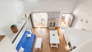Una habitación con techo alto, una mesa blanca, un sofá azul, un banco blanco y una pared con diseño.