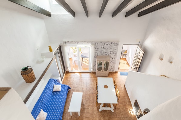 A room with a high ceiling, a white table, a blue sofa, a white bench, and a patterned wall.