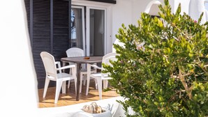 Un patio con mesa y sillas, una puerta corrediza de vidrio y una pared blanca.
