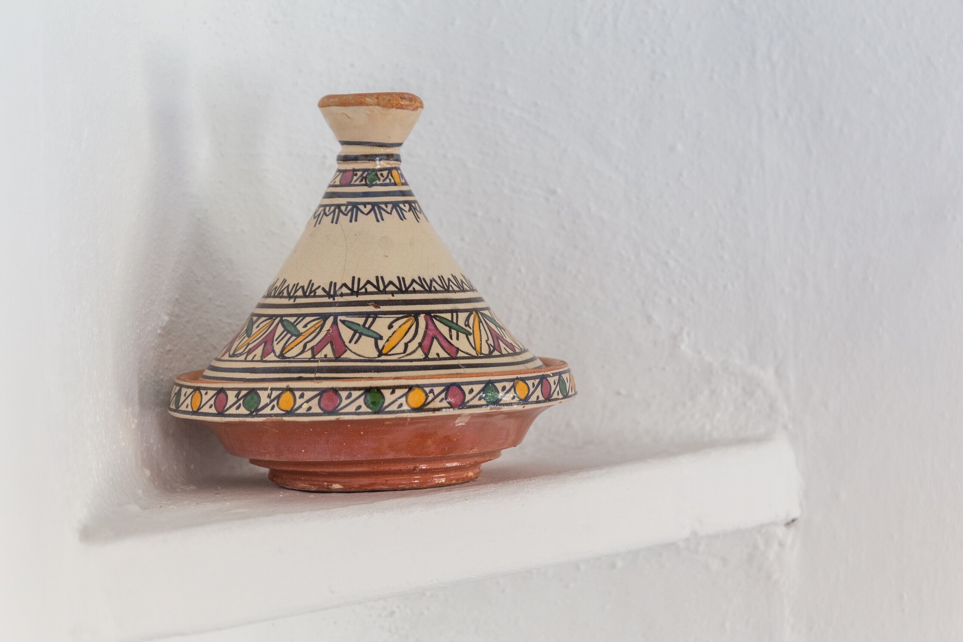 A ceramic pot with a narrow neck and a wide base, decorated with geometric patterns.
