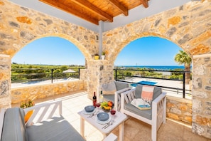 Un espace extérieur aménagé avec des murs en pierre, offrant une vue sur la piscine, une table dressée pour le repas et un plafond en bois.