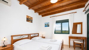 Un dormitorio con dos camas, un escritorio, una silla, una ventana con vistas y un ventilador de techo.