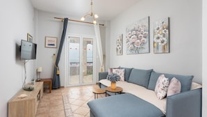 A modern living room with a sofa, a TV, and artwork on the wall. - Michalis - Three Bedroom Villa, Sleeps 6 (Nisaki)