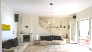 A living room with a fireplace, a staircase, and a glass door leading outside. - Villa Asteria directly on the beach (Campo nell'Elba)