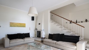 A living room with two sofas, a glass coffee table, a fireplace, and a staircase. - Villa Asteria directly on the beach (Campo nell'Elba)
