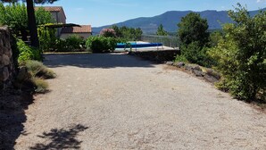 A gravel driveway leading to a house with a pool, surrounded by greenery and mountains in the background. - Le Vignal 2, cottage with 2 bedrooms in the south of the Ardèche (Chambonas)