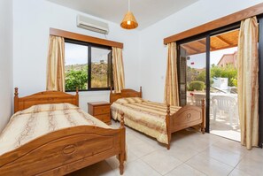 Ein Schlafzimmer mit zwei Holzbetten, einem Fenster, einer Klimaanlage und Blick ins Freie.