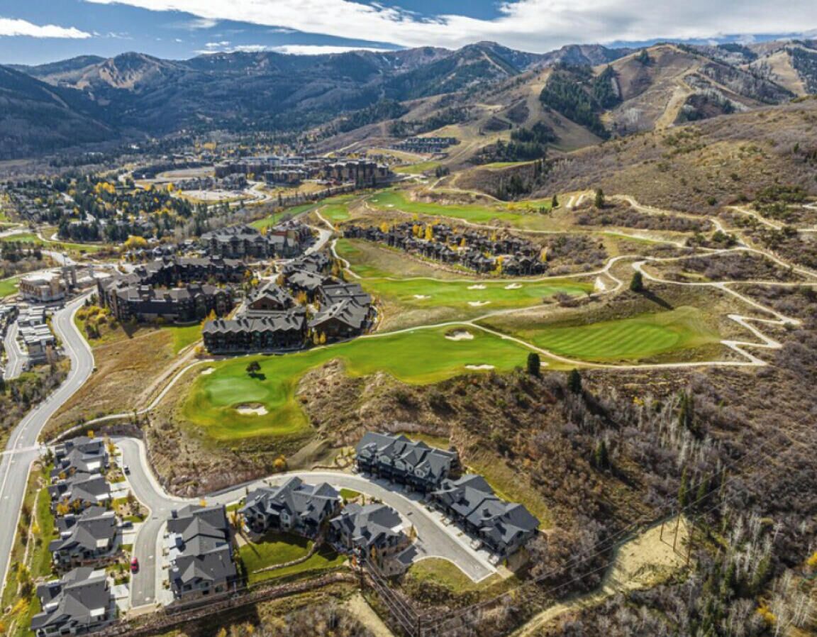 An aerial view of a residential area with houses, roads, and a golf course.