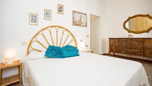 Un dormitorio con cama, cabecera de madera, cómoda, espejo y decoración en la pared.