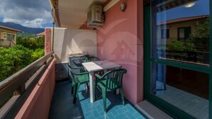 Un balcon avec une table et des chaises, une fenêtre donnant sur des immeubles et un logo en forme de maison sur le mur.