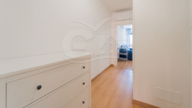 Un couloir étroit avec une commode blanche et un plancher en bois.