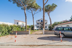 Un quartier résidentiel avec un immeuble de deux étages, une voiture garée et des arbres.