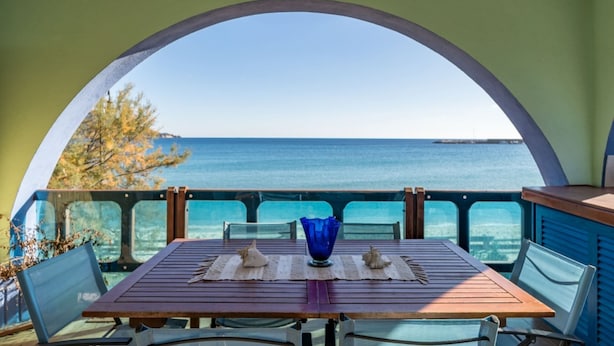 Una mesa con vista al mar a través de un ventanal arqueado.