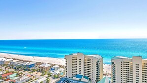 A beachfront hotel with multiple buildings, a parking area, and a view of the ocean.
