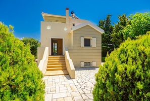 Une maison à deux étages avec un escalier en pierre menant à l’entrée.