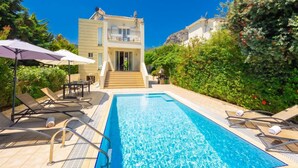A swimming pool with sun loungers and a staircase leading to a building.