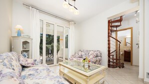 A living room with a sofa, a glass-top coffee table, and a staircase leading to another room.