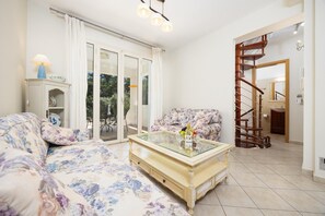 A living room with a sofa, a glass-top coffee table, and a staircase leading to another room. - Villa Semeli - Two Bedroom Villa, Sleeps 5 (Ionian Islands)