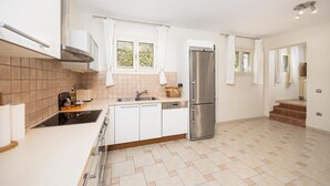 A modern kitchen with a stainless steel refrigerator, white cabinets, and a tiled floor.