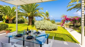 A glass table set outdoors with a view of the sea and palm trees. - Villa Sevos - Two Bedroom Villa, Sleeps 4 (Crete)