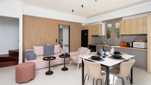 A modern living room with a sofa, coffee table, and dining table set up for a meal. - Villa Sevos - Two Bedroom Villa, Sleeps 4 (Crete)