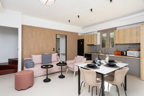 Ein modernes Wohnzimmer mit Sofa, Couchtisch und Esstisch, gedeckt für eine Mahlzeit.
