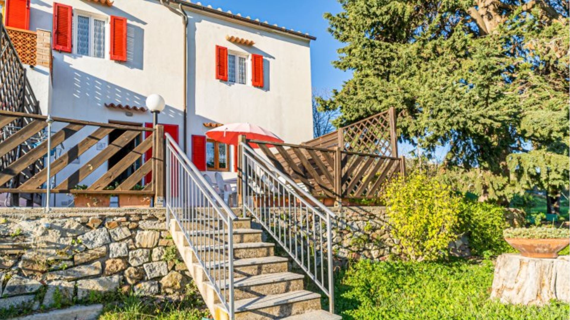 Un bâtiment à deux étages avec un escalier en pierre menant à une terrasse en bois.