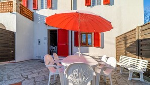 Un espace extérieur aménagé avec une table et des chaises, un parasol rouge et une clôture en bois.