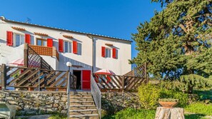 Stunning two-story building with a stone staircase and charming red shutters.