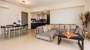 A modern living room with a sectional sofa, dining area, and kitchen.
