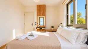 A bedroom with a bed, a bedside table, a mirror, a window, and a door.